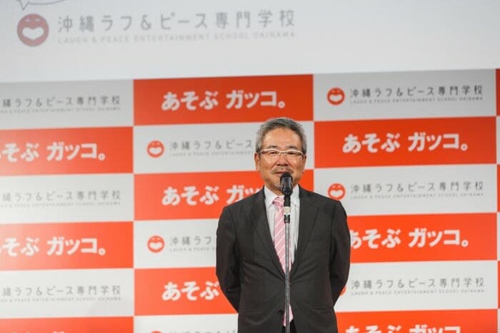 Nobuhiko Horie takes the stage at a press conference announcing the outline of “Okinawa Rough & Peace College”